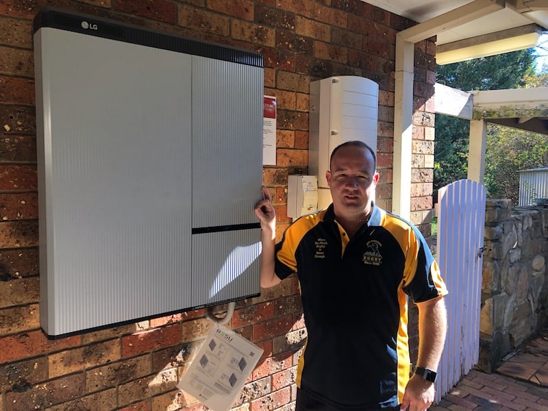 Picture of a client standing and pointing to his battery storage