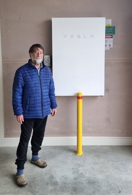 Picture of a client standing and pointing to his battery storage
